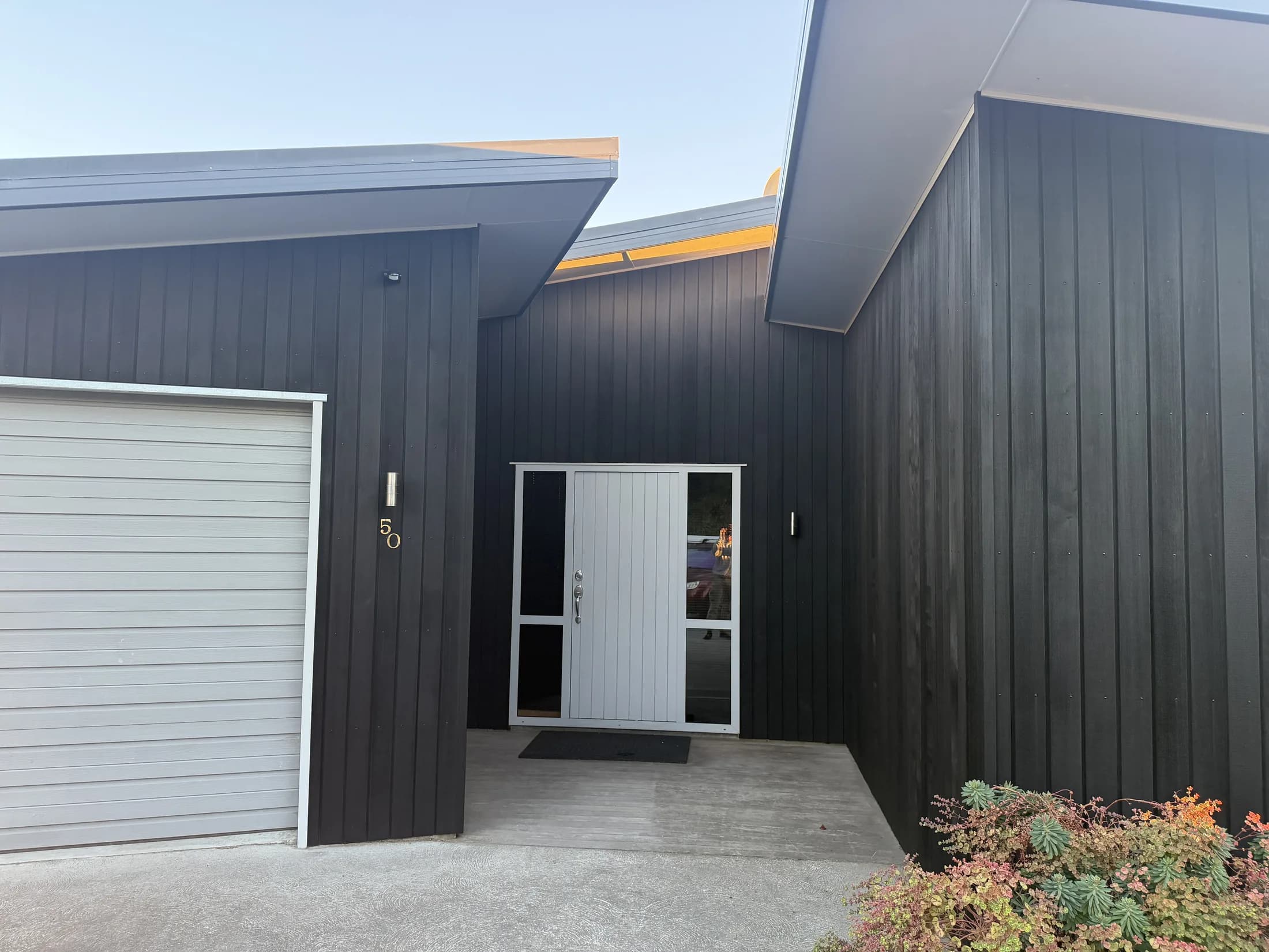 Black stained cedar cladding at the front entry of a home in Wanaka